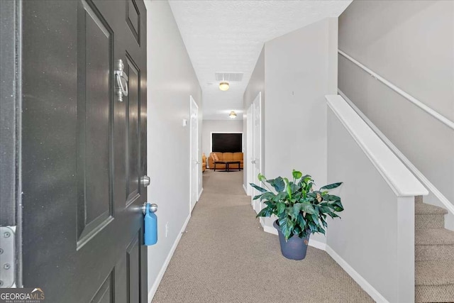 hallway featuring a textured ceiling and light carpet