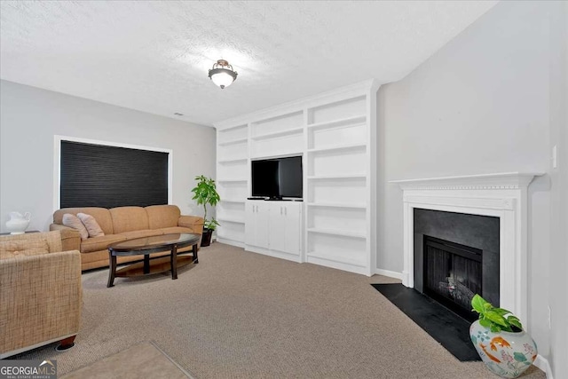 living area featuring a textured ceiling, dark colored carpet, built in shelves, and a fireplace with flush hearth