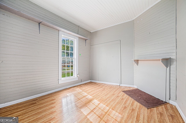 unfurnished living room featuring hardwood / wood-style floors, wooden walls, and crown molding