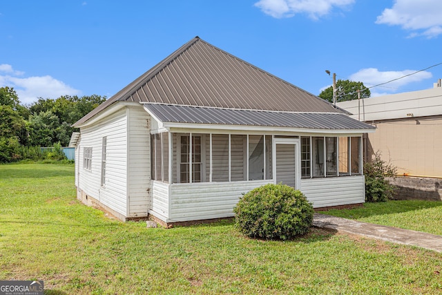 rear view of house with a sunroom and a lawn