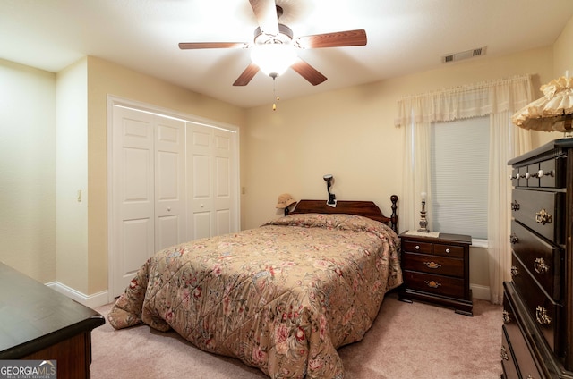 bedroom with a closet, ceiling fan, and light carpet