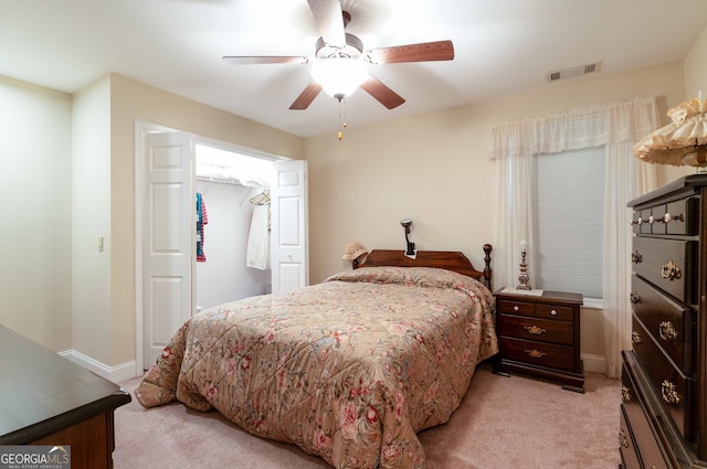 bedroom with light colored carpet, ceiling fan, and a closet