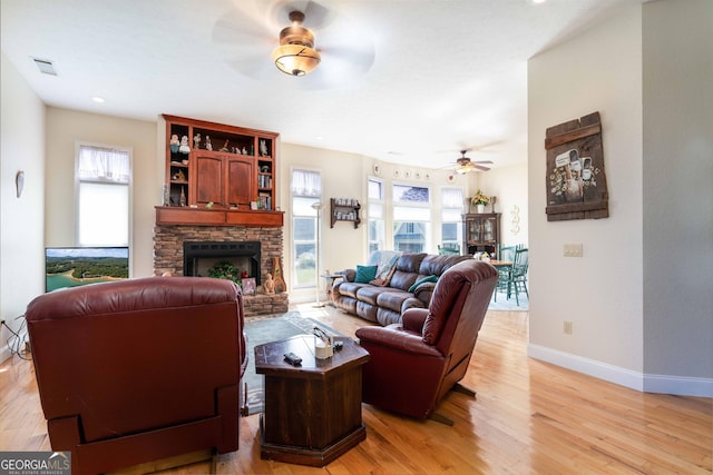 199 Colonsay Trce, Blairsville, GA 30512 - living area featuring light wood-type flooring, visible vents, a fireplace with raised hearth, a ceiling fan, and a healthy amount of sunlight