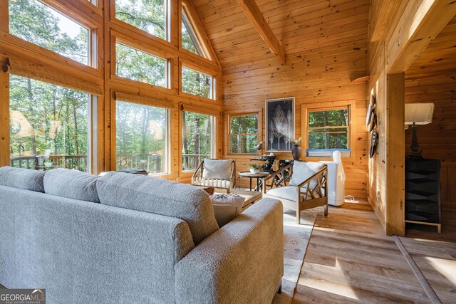 living room featuring a wealth of natural light, wood walls, hardwood / wood-style floors, and high vaulted ceiling