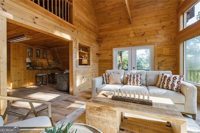 living room with a wealth of natural light, high vaulted ceiling, wooden walls, and hardwood / wood-style flooring