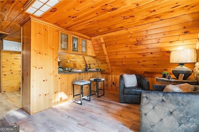 living area featuring wooden ceiling, vaulted ceiling, wooden walls, and light hardwood / wood-style floors