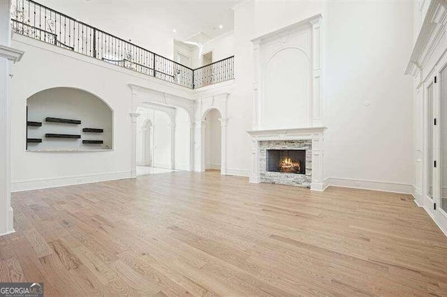 unfurnished living room featuring a high ceiling, hardwood / wood-style flooring, and a stone fireplace