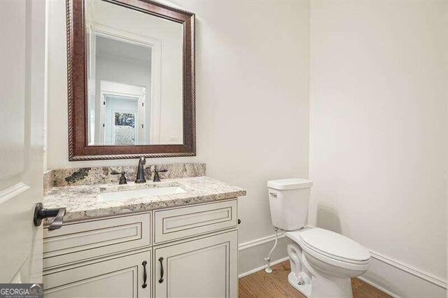 bathroom with vanity, toilet, and hardwood / wood-style floors