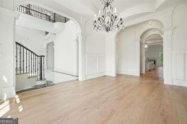 unfurnished living room with ornamental molding, decorative columns, and light hardwood / wood-style floors