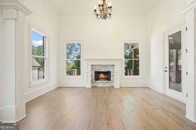 unfurnished living room with a fireplace, a notable chandelier, and light hardwood / wood-style flooring