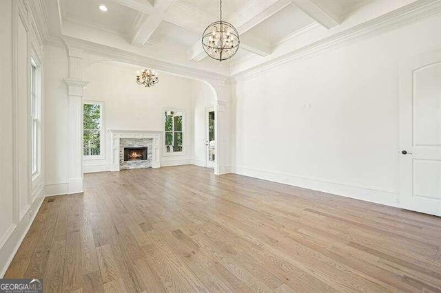 unfurnished living room with coffered ceiling, hardwood / wood-style flooring, a chandelier, and beamed ceiling