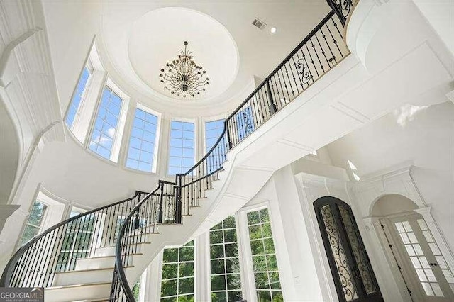 stairway with a towering ceiling and an inviting chandelier