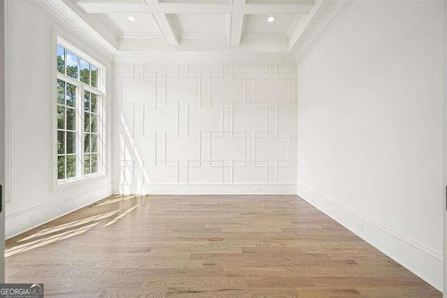 empty room with coffered ceiling, a healthy amount of sunlight, and wood-type flooring