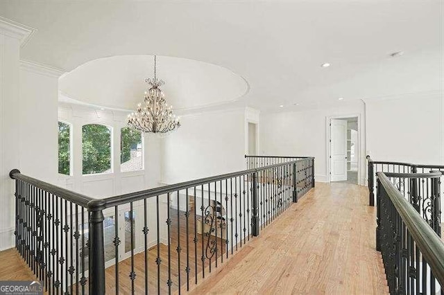 hallway with crown molding, a chandelier, and light hardwood / wood-style floors