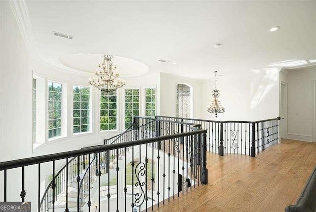 hall featuring hardwood / wood-style flooring, crown molding, and a notable chandelier