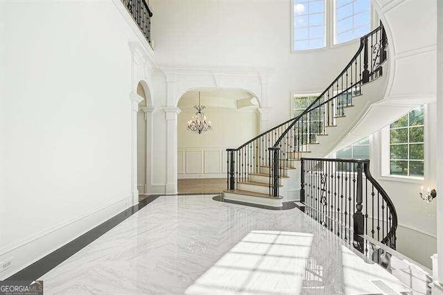 stairway with a towering ceiling, hardwood / wood-style floors, and a chandelier