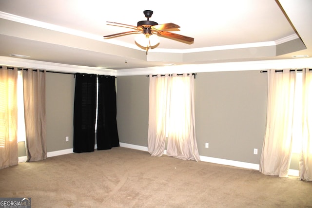 carpeted empty room with a tray ceiling, ceiling fan, and ornamental molding