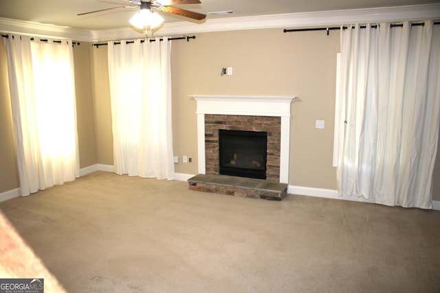 unfurnished living room featuring ceiling fan, a stone fireplace, light colored carpet, and crown molding