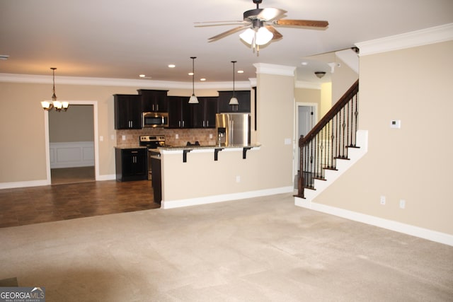 kitchen with decorative light fixtures, a kitchen bar, ceiling fan with notable chandelier, and appliances with stainless steel finishes