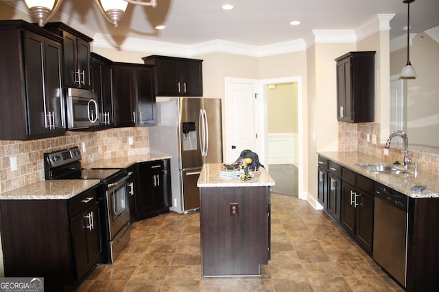 kitchen with appliances with stainless steel finishes, crown molding, sink, decorative light fixtures, and a kitchen island