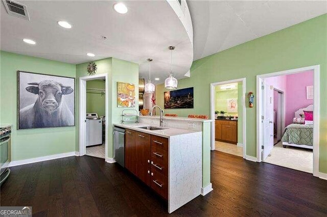 kitchen with dishwasher, dark hardwood / wood-style flooring, independent washer and dryer, and sink