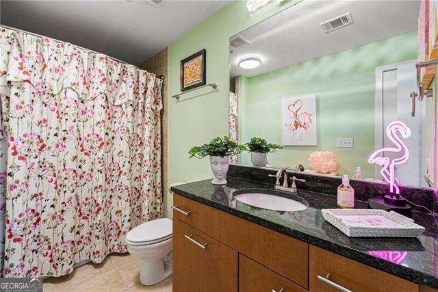 bathroom with tile patterned flooring, vanity, toilet, and curtained shower