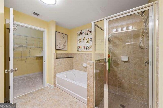 bathroom with tile walls, independent shower and bath, and tile patterned flooring