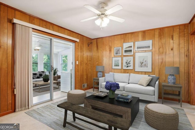 living room with light carpet, ceiling fan, wood walls, and visible vents