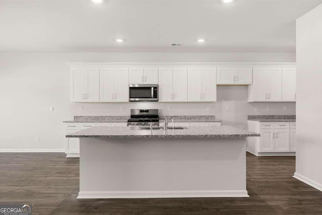 kitchen with a center island with sink, white cabinetry, light stone countertops, and range