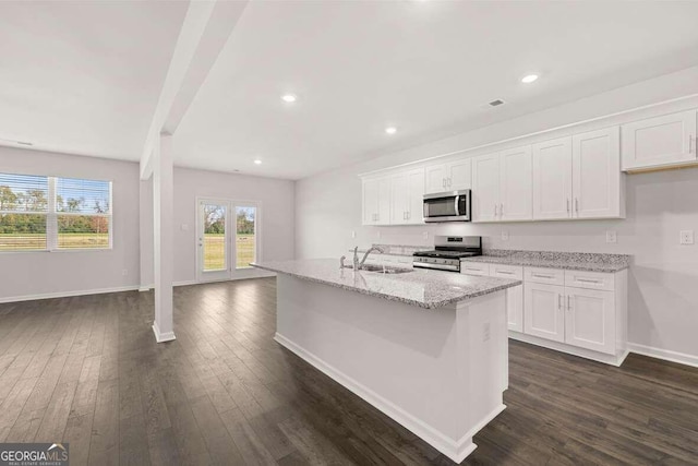 kitchen featuring appliances with stainless steel finishes, white cabinetry, sink, dark wood-type flooring, and a center island with sink