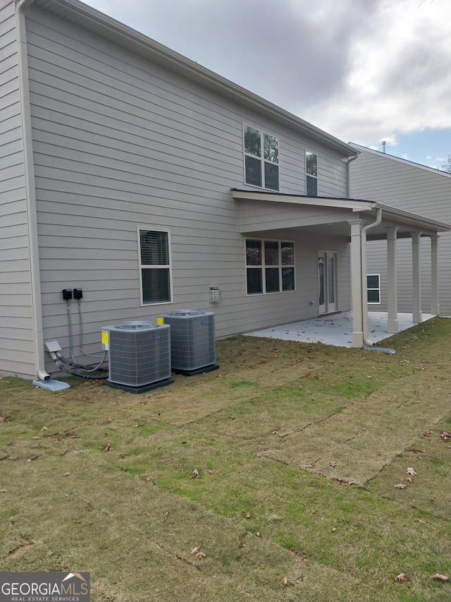 rear view of property featuring cooling unit, a yard, and a patio area