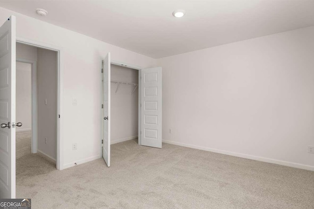 unfurnished bedroom featuring light carpet and a closet