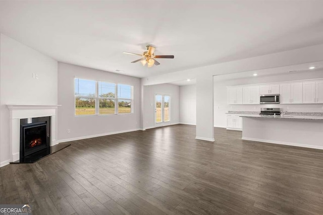 unfurnished living room featuring ceiling fan and dark hardwood / wood-style floors