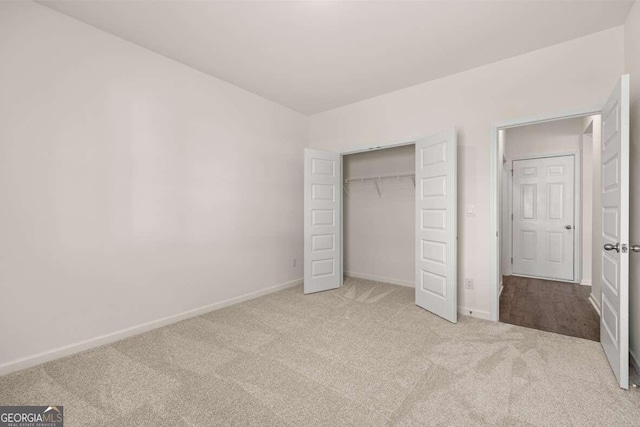 unfurnished bedroom with light colored carpet and a closet