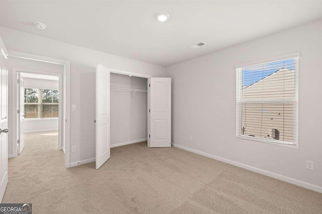 unfurnished bedroom featuring light colored carpet and a closet