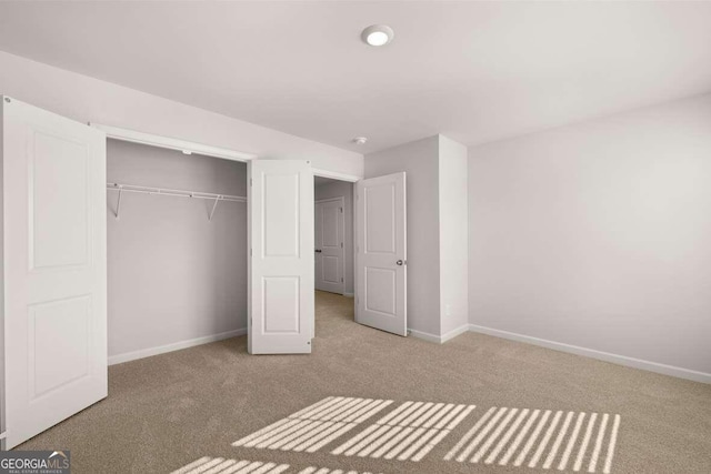 unfurnished bedroom with light colored carpet and a closet