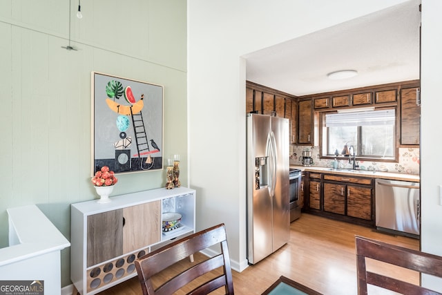 kitchen featuring tasteful backsplash, stainless steel appliances, sink, and light hardwood / wood-style floors