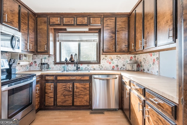 kitchen with sink, appliances with stainless steel finishes, and light hardwood / wood-style floors