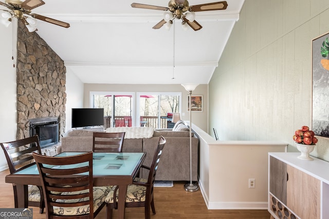 dining area with ceiling fan, hardwood / wood-style flooring, vaulted ceiling with beams, and a fireplace