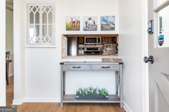 bar featuring light hardwood / wood-style flooring and stainless steel appliances