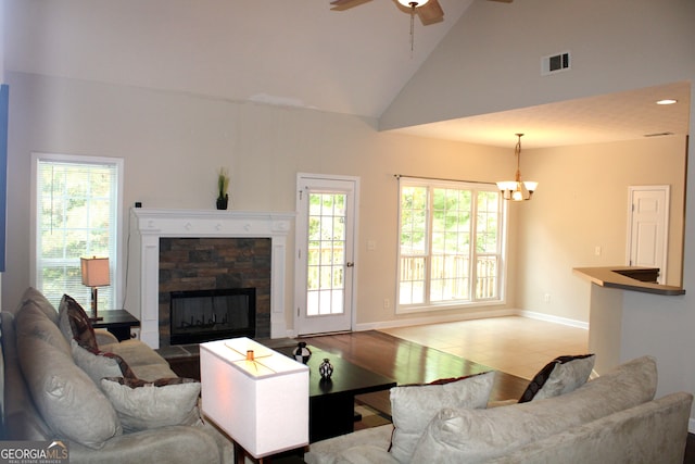 living room with hardwood / wood-style floors, ceiling fan with notable chandelier, high vaulted ceiling, and a fireplace