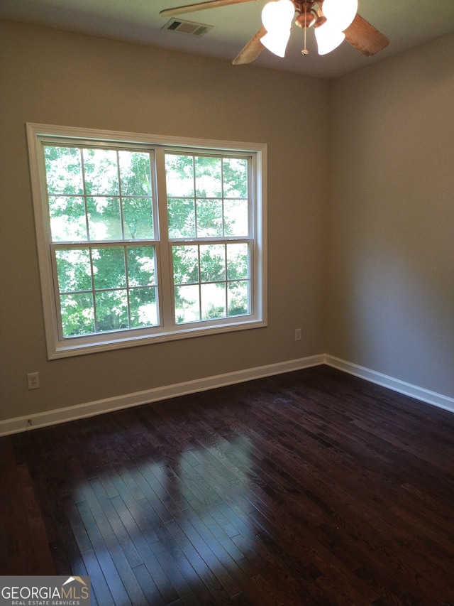 spare room featuring dark wood-type flooring, ceiling fan, and a wealth of natural light