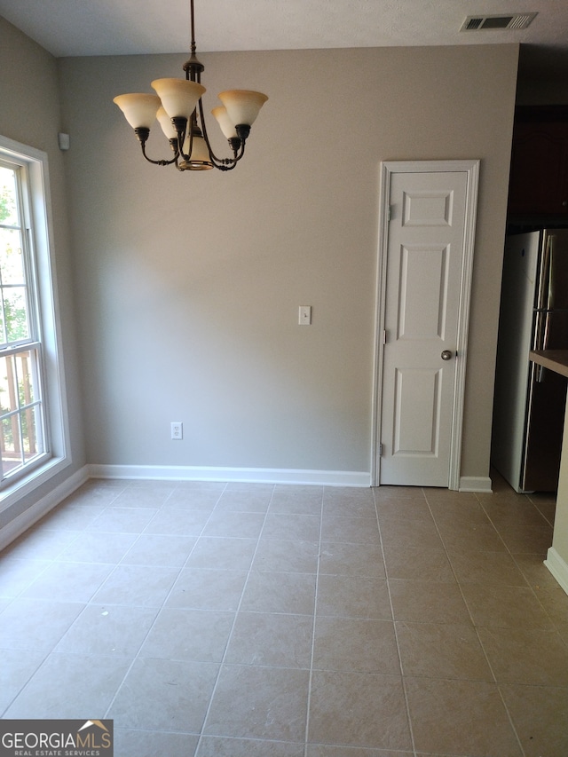 unfurnished dining area with light tile patterned floors and an inviting chandelier