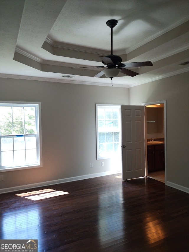 interior space with a tray ceiling, ornamental molding, hardwood / wood-style floors, and multiple windows