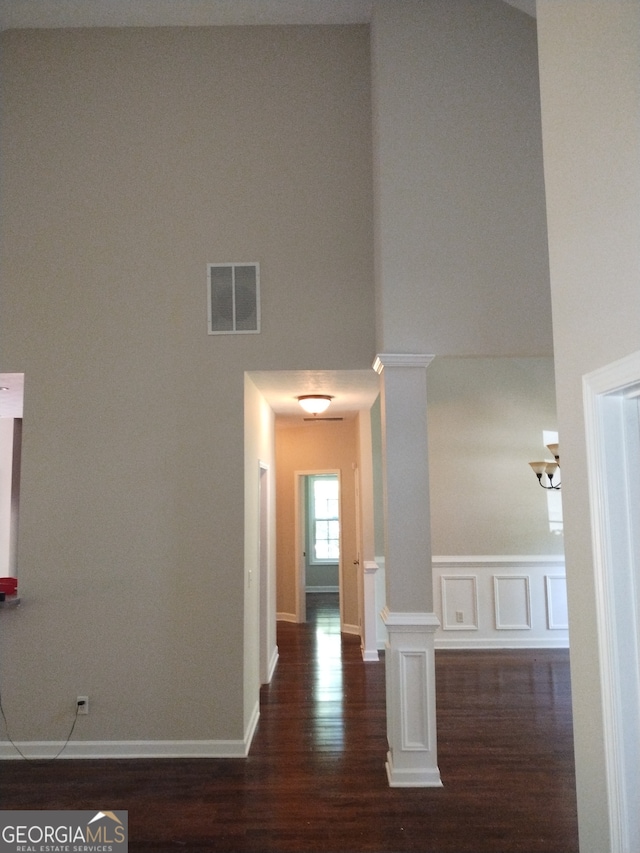 interior space with a high ceiling, decorative columns, and dark hardwood / wood-style floors