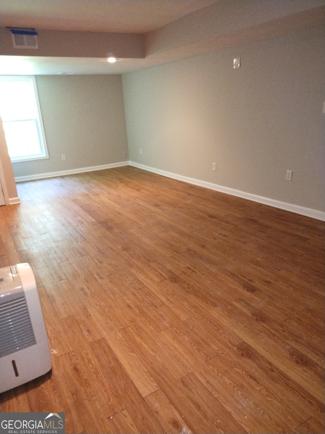 empty room featuring wood-type flooring and heating unit