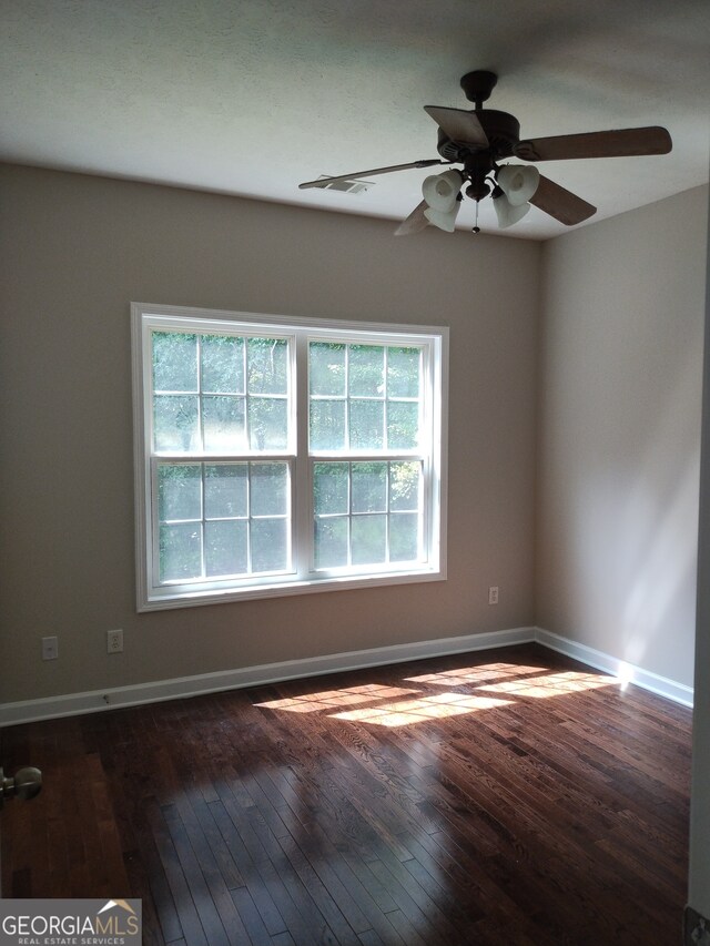 unfurnished room featuring ceiling fan, a wealth of natural light, and dark hardwood / wood-style floors