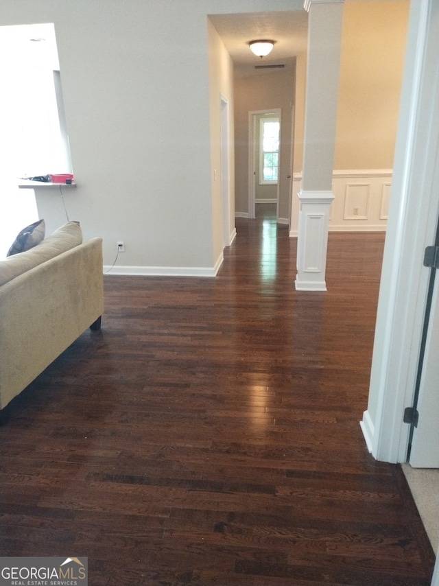 hallway with dark hardwood / wood-style flooring and decorative columns