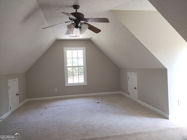 additional living space with lofted ceiling, ceiling fan, light carpet, and a textured ceiling