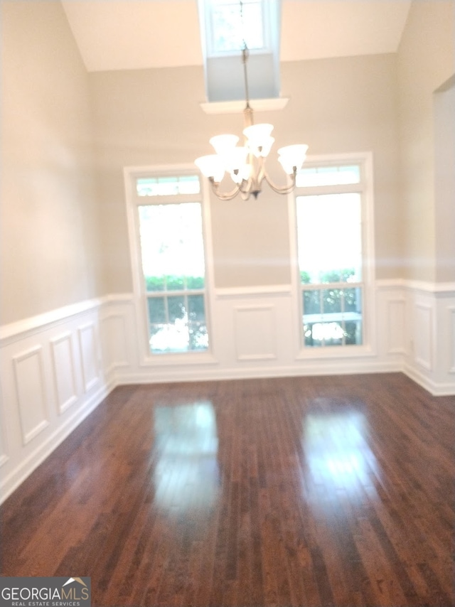 unfurnished dining area featuring dark hardwood / wood-style flooring, a wealth of natural light, and an inviting chandelier